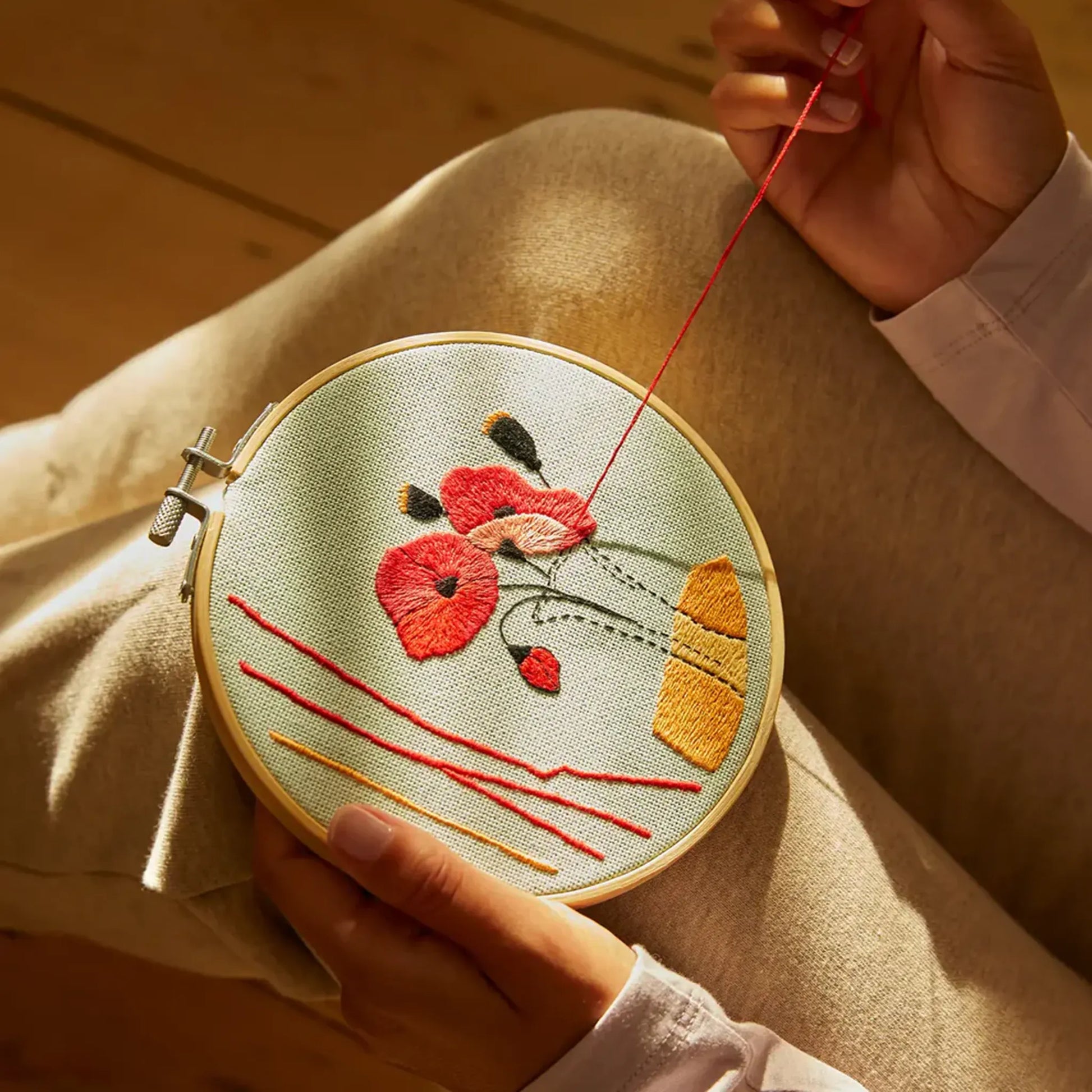 Person stitching a bright floral design in an embroidery hoop