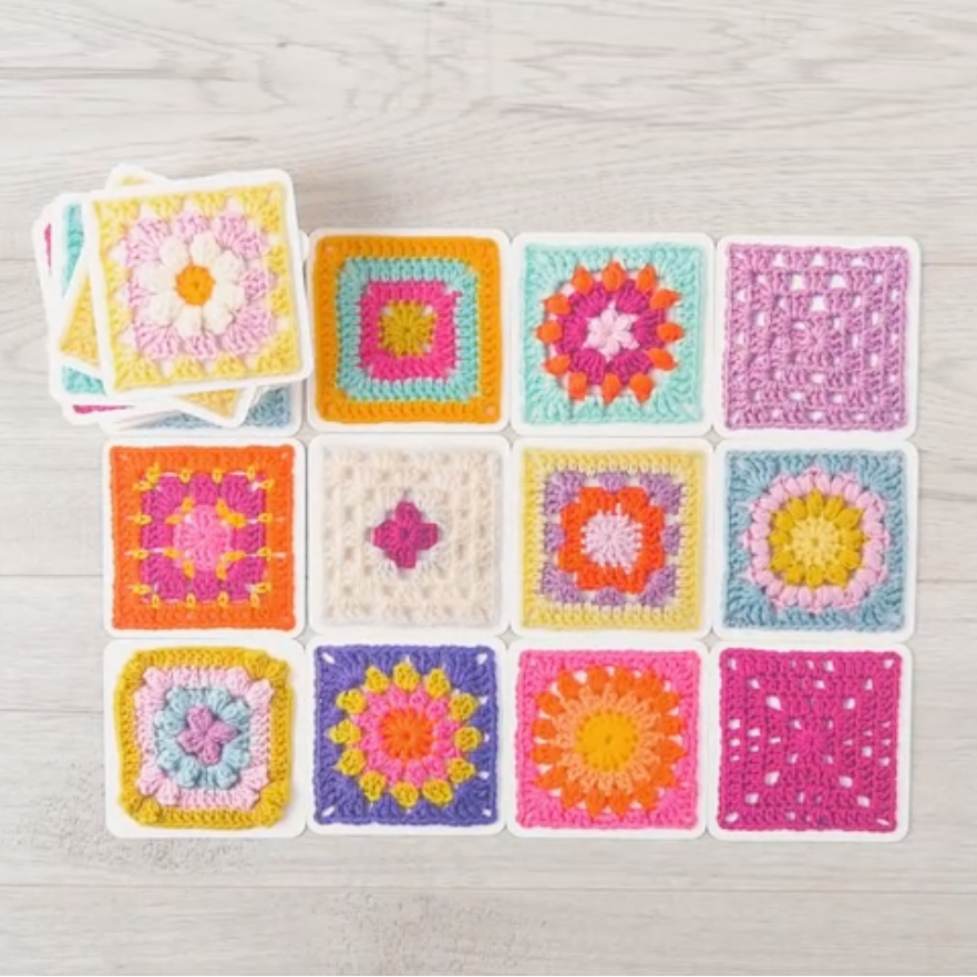 Colourful crochet squares on a light wooden surface
