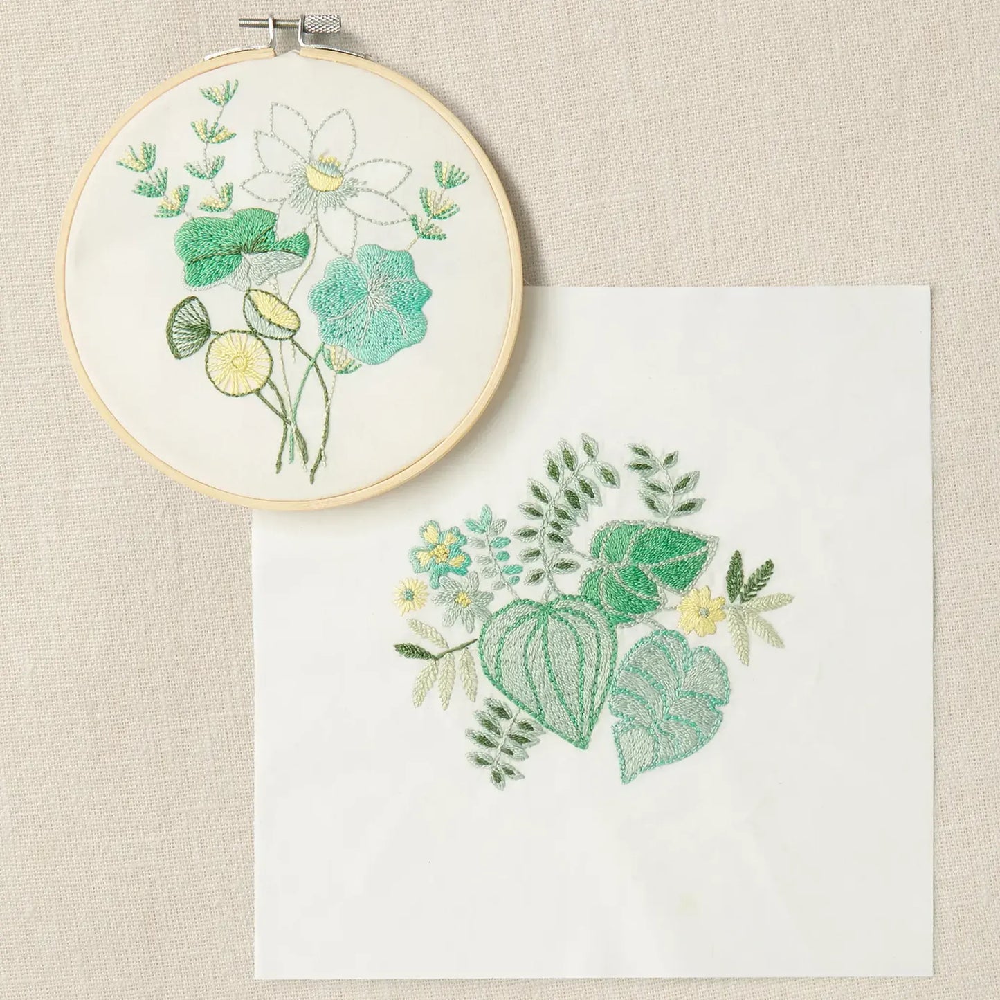 Completed embroidery on cream fabric with a coordinating botanical design in soft green tones