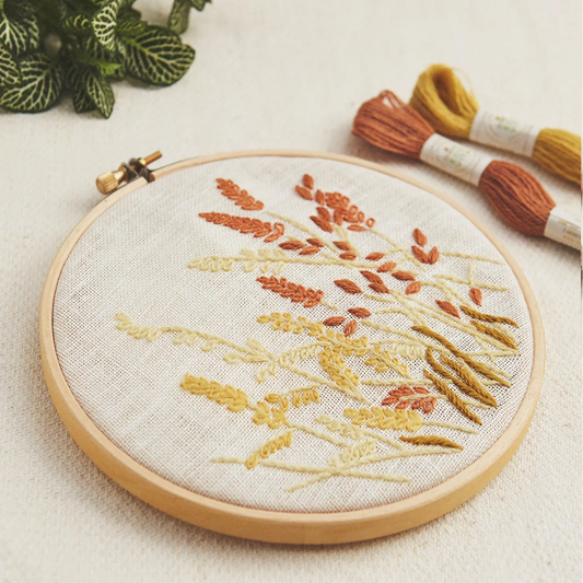 Embroidery hoop with wheat botanical design in autumnal tones on a light background